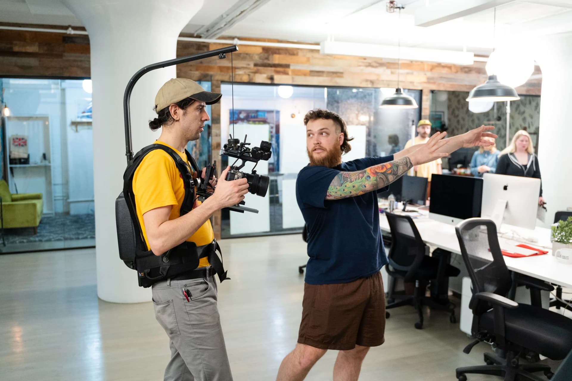 a man is holding a camera while standing next to another man in an office .