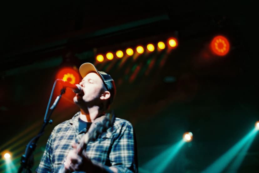 a man is playing a guitar and singing into a microphone on a stage .
