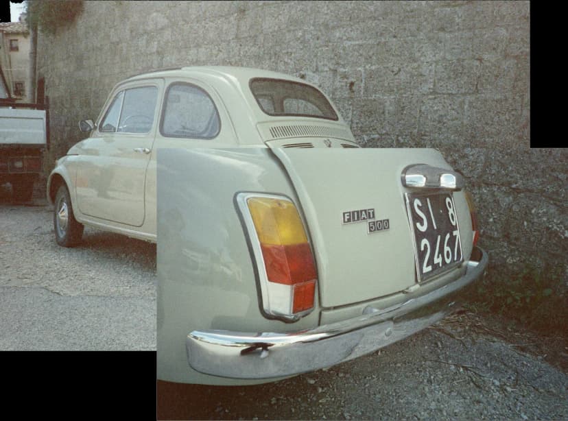 a fiat 500 is parked in front of a stone wall