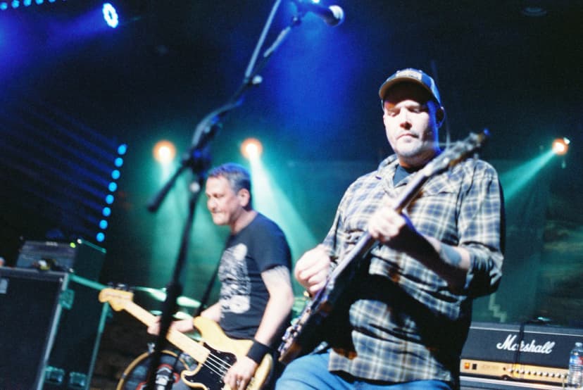 two men are playing guitars on a stage in front of a microphone .