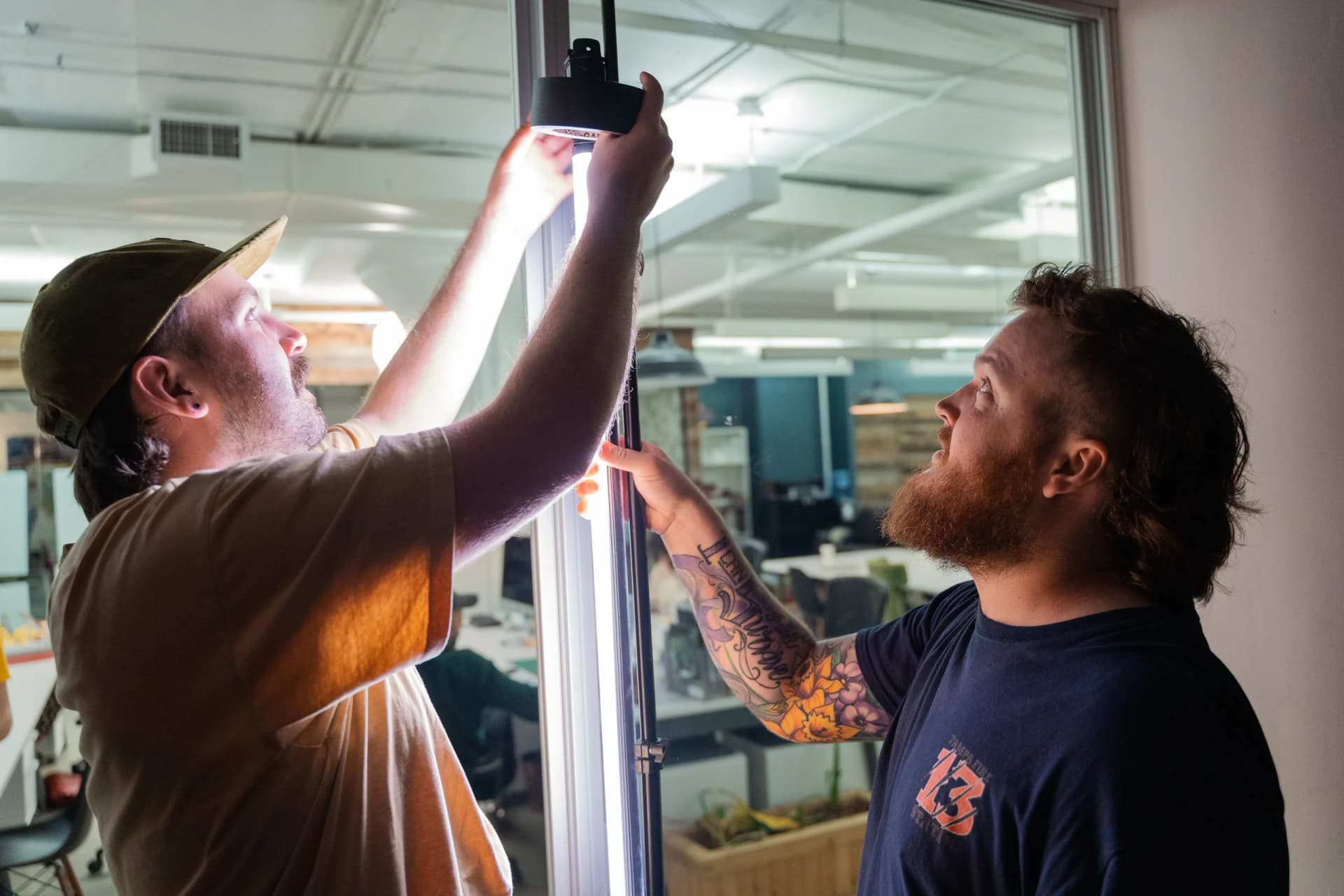 two men are working on a light fixture in a room .