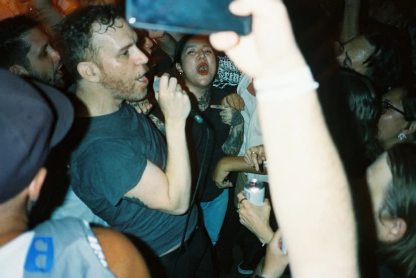 a man is singing into a microphone in a crowd of people at a concert .