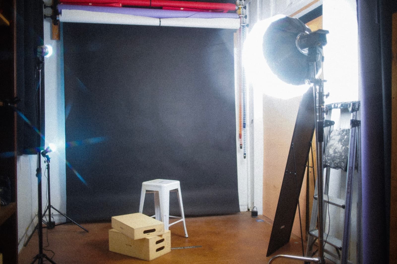 Photo studio with seamless paper backdrops, a softbox light, and apple boxes